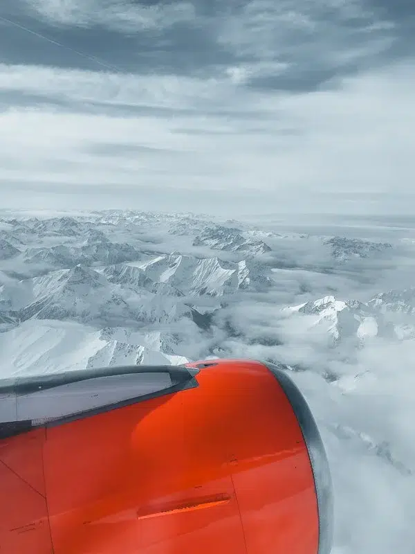 A red plane engine flying over snowy mountains in the Austrian aps