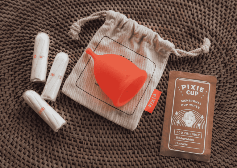 Pink menstrual cup and tampons which are both zero waste travel toiletry options