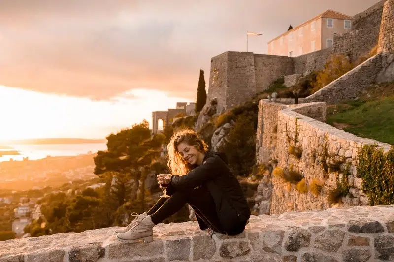 Woman sitting on a stone wall at Klis Fortress in Split Croatia