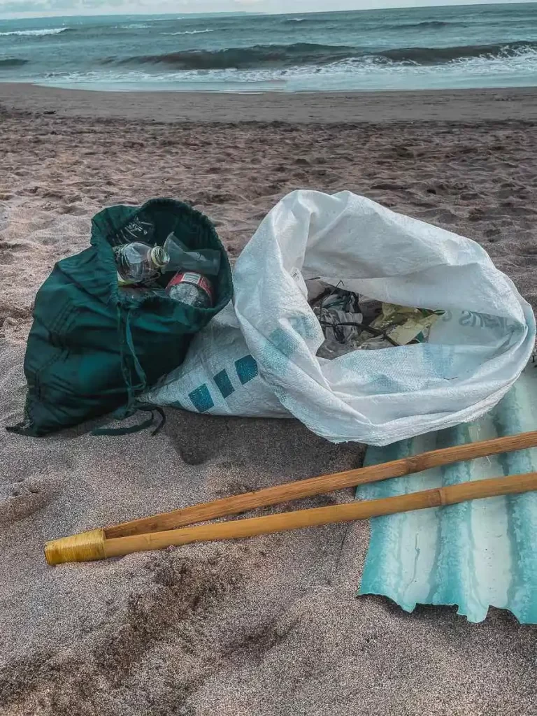 Two bags of trash on the beach, collected by volunteers in Bali