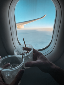 Two people clinking cups on an airplane, on the way to travel Europe!